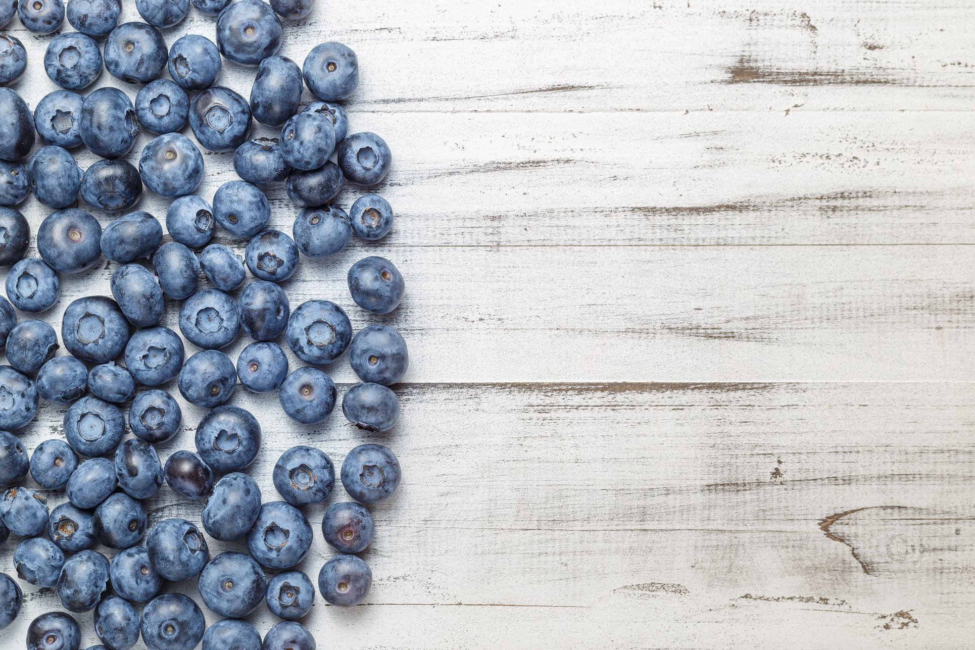 American blueberries scattered over white wooden background